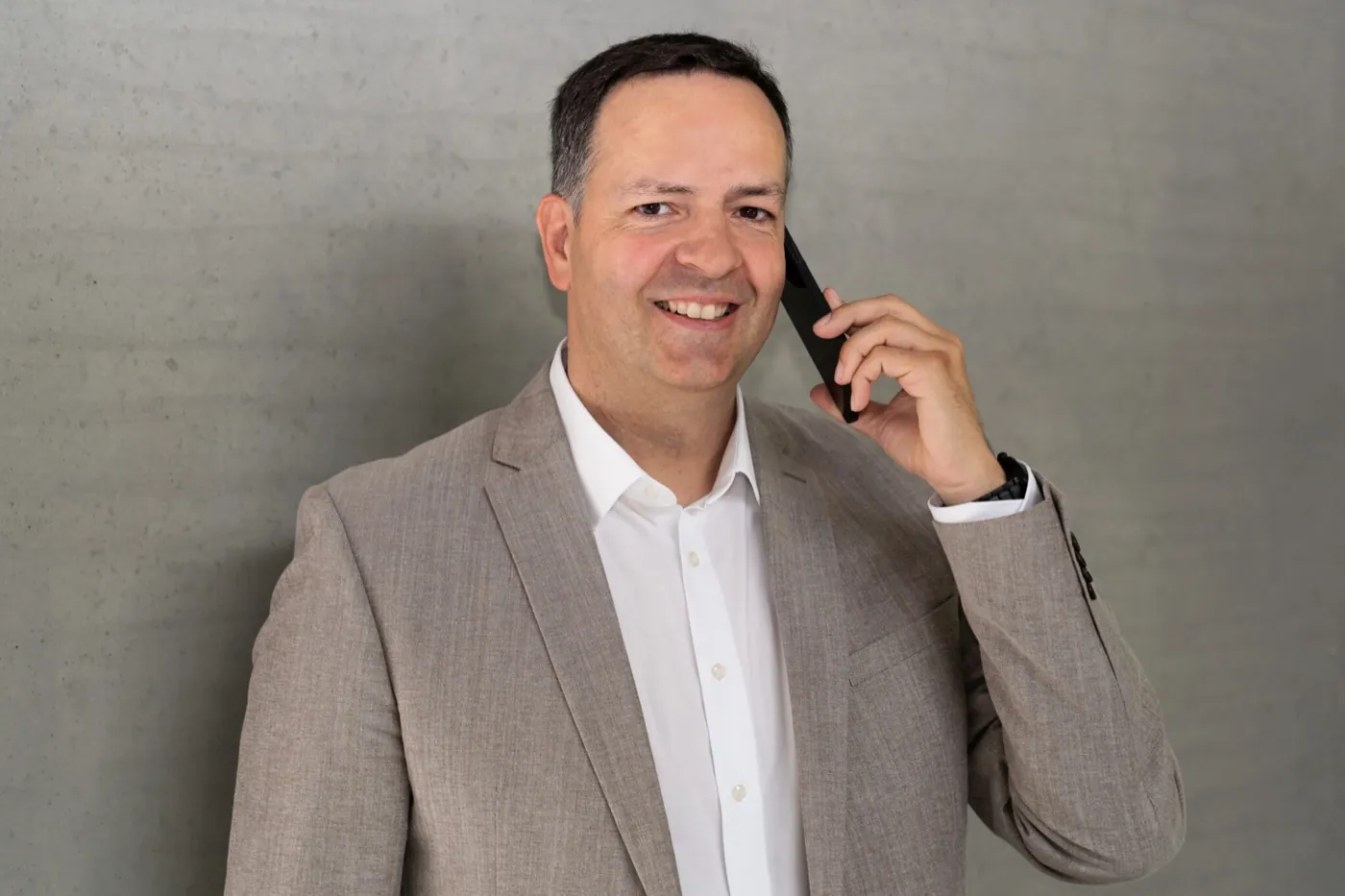 Dr. Sven Lorenz telefoniert lächelnd vor einer Betonwand